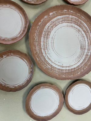 Set of ceramic plates with white interior glaze on a green surface