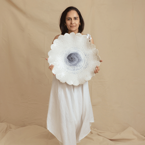Woman holding a large white flower-like object against a beige background