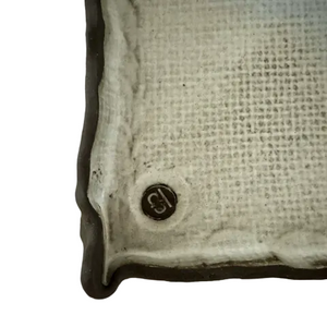Corner of a textured ceramic item with a logo on a white background