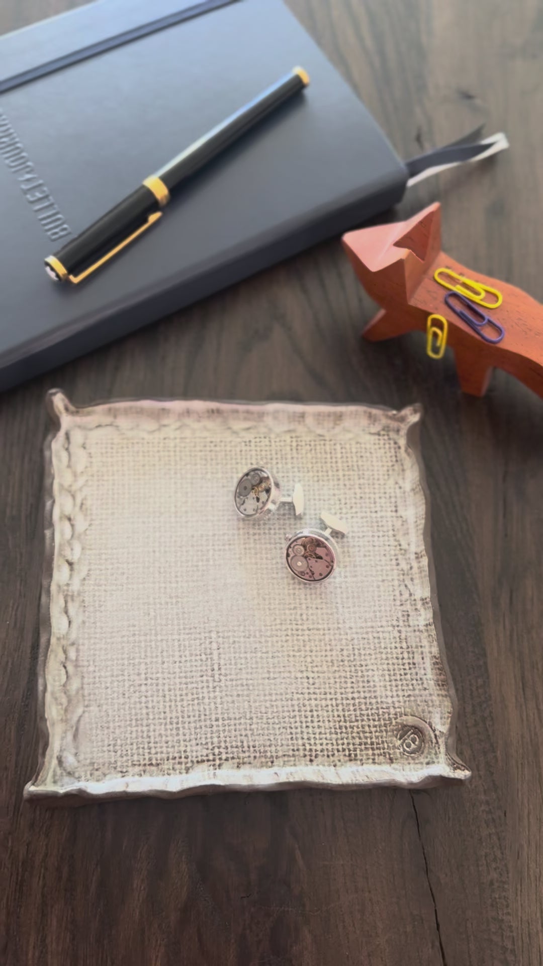 Pen and cufflinks on a textured surface with a blurred background